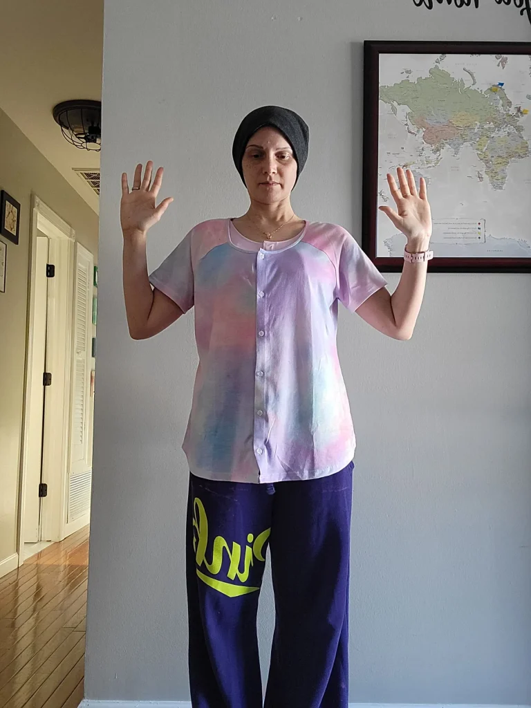 A women standing with her arms raised at about the height of her head.
