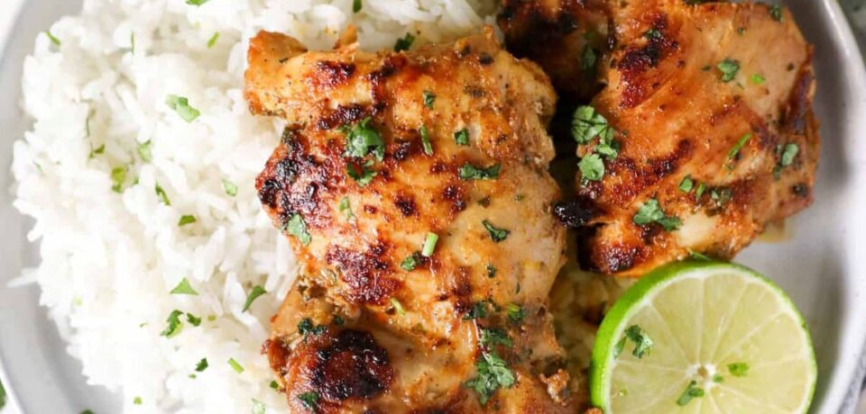 plate with white rice, cut limes, and two pieces of cilantro chicken