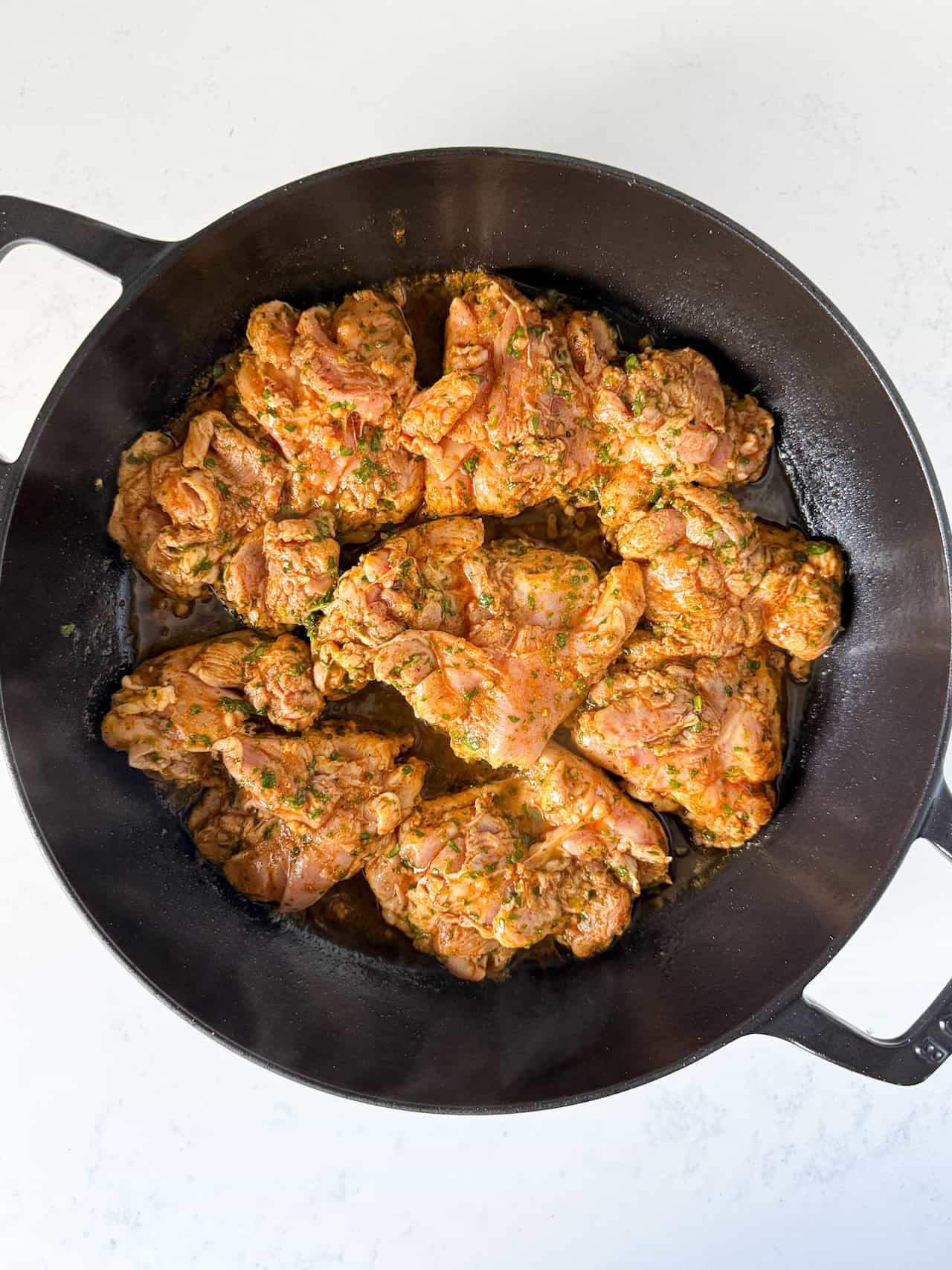 skillet full of marinated uncooked chicken