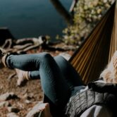 woman sitting on hammock beside calm water