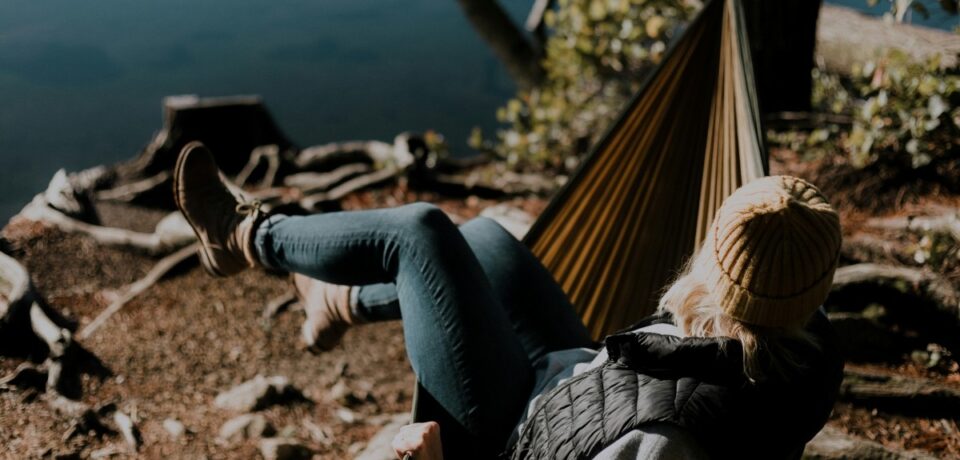 woman sitting on hammock beside calm water