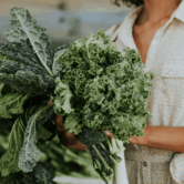 a women shopping holding a bundle of leafy greens in her hand