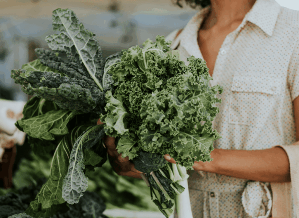 a women shopping holding a bundle of leafy greens in her hand